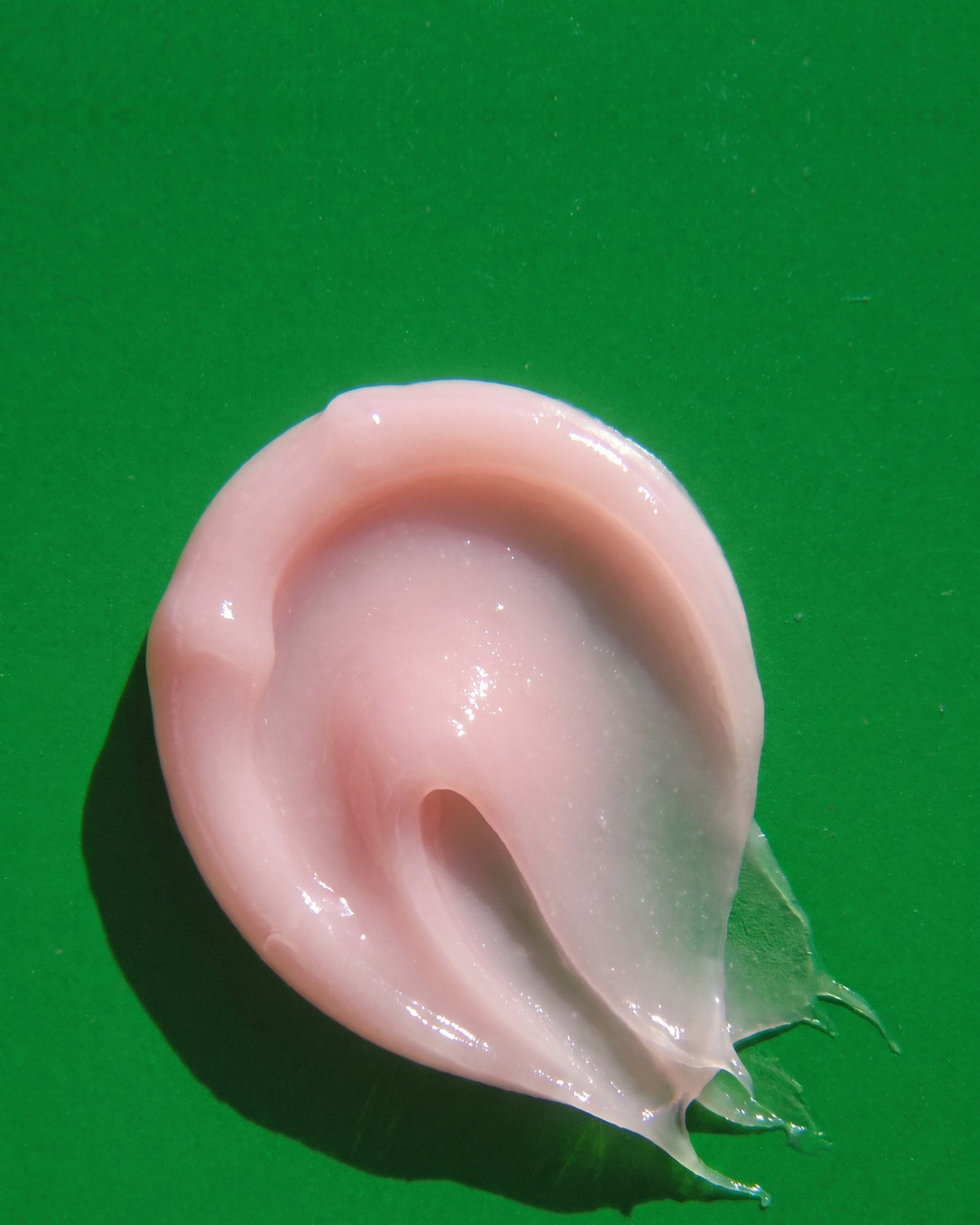 A glossy swirl of Lipcure Balm on a green surface