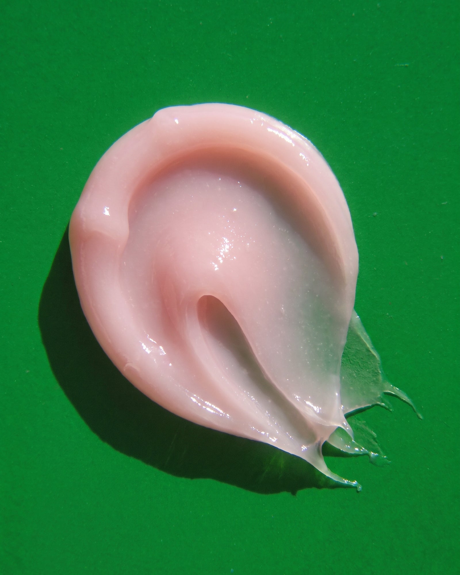 A glossy swirl of Lipcure Balm on a green surface