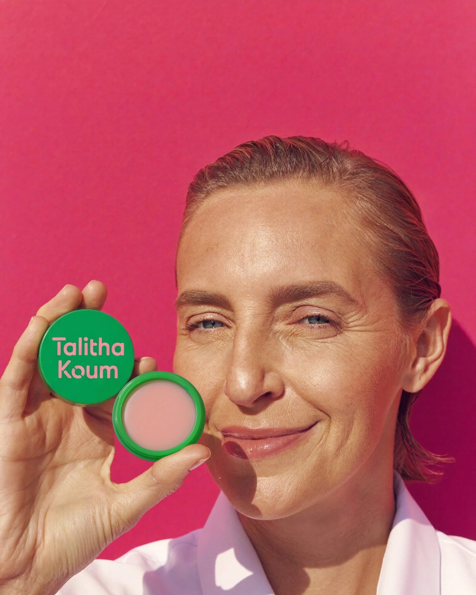A model holding an open Lipcure Balm tin