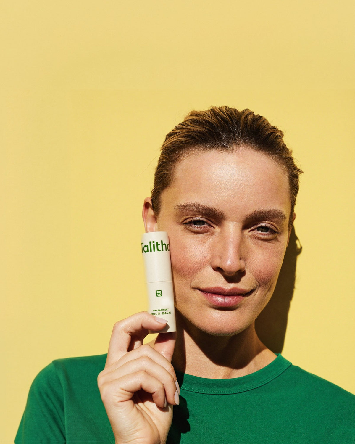 A model holding Multi Balm stick against her cheek
